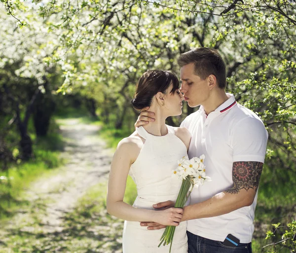 Young are kissing couple under the  big tree with flowers at sunset, concept of the first date. Just marriage