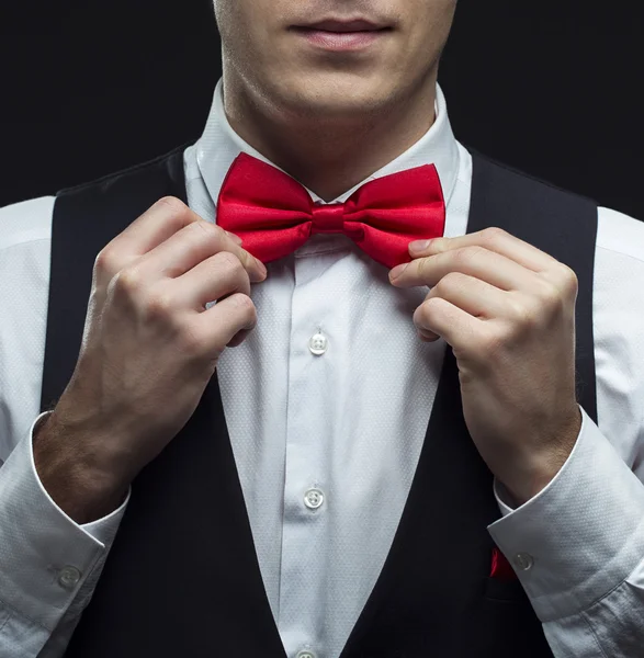 Handsome elegant young fashion man in black classical costume suit, white shirt and red bow tie