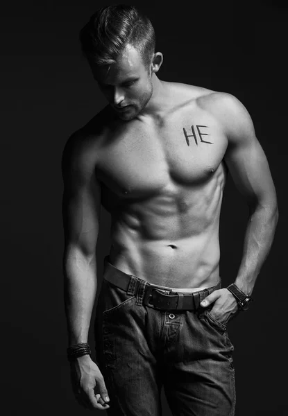 Handsome muscular male model with intense glance posing over grey background. Perfect body with the inscription 