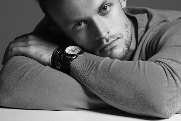 Advertising wrist watch concept. Beautiful (handsome) muscular male model with perfect body in grey jumper and with the clock on his hand. Street style. Black and white, monochrome studio shot