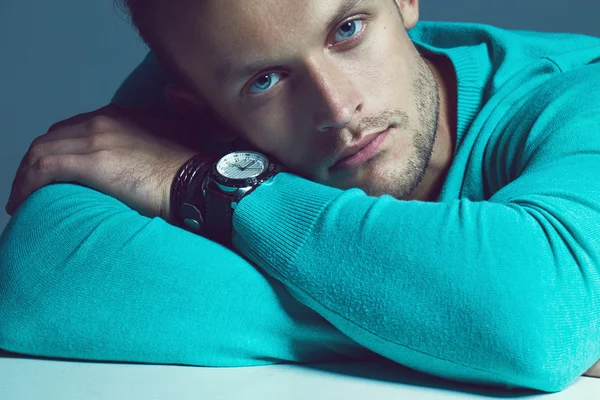 Advertising wrist watch concept. Beautiful (handsome) muscular male model with perfect body in blue jumper and with the clock on his hand. Street style. Black and white, monochrome studio shot