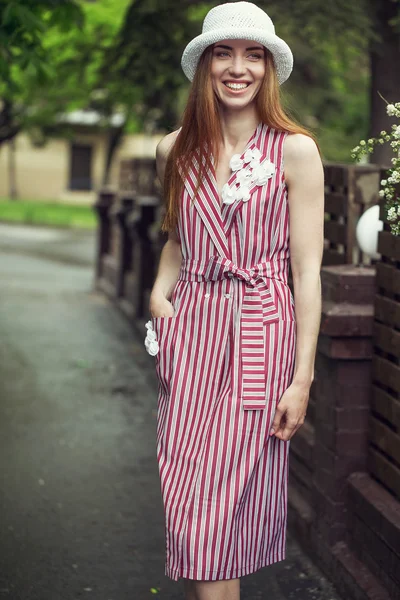 Beautiful stylish young girl dressed in casual clothes (dress and sneakers) walks through the streets of the city after the rain. the concept of fashion wear for women