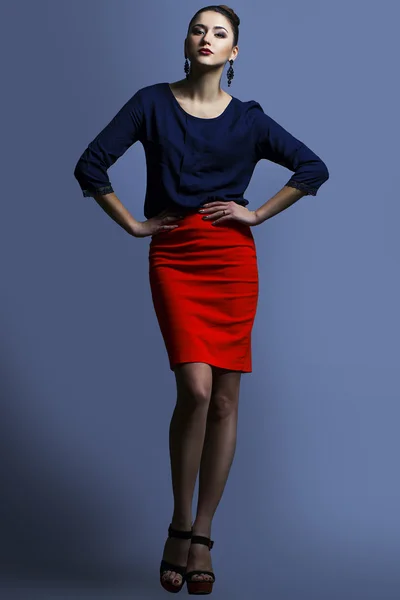 High fashion look. Portrait of a fashionable model with sexy red lips, beautiful red skirt and blue shirt. Studio shot