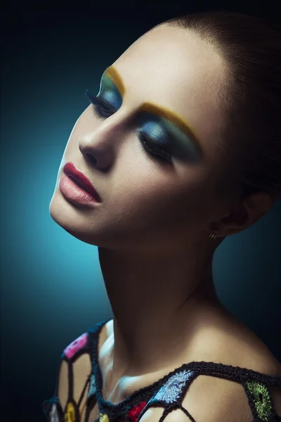 Close-up of beautiful female face with colorful make-up.Beauty.  Fresh glowing skin. Blue.Art.Theater.Face art.Bright.Closeup.Portrait.Look Fashion make-upt.Fantastic Modern production