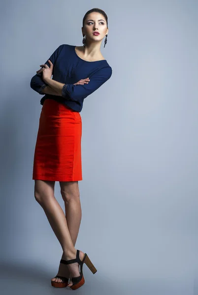 High fashion look of a running girl. Portrait of a fashionable model with sexy red lips, beautiful red skirt and blue shirt. Studio shot
