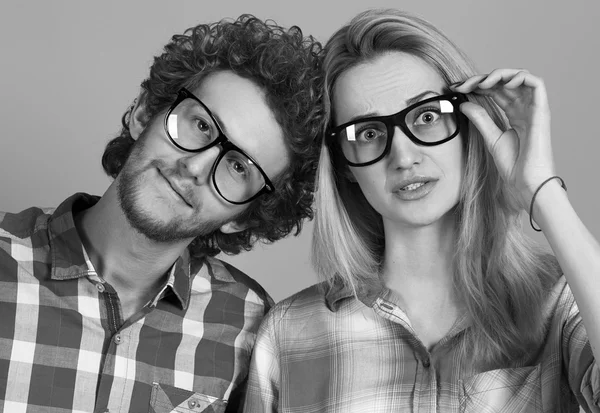 Portrait of gorgeous blond fashion man and woman in casual shirt, wearing trendy glasses posing on blue background. Perfect skin and hairdo. Vogue style. Close up. Studio shot.