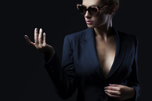 Portrait of a beautiful girl posing in studio in black jacket and fashion sunglasses. The concept of stylish and sexy women. perfect skin and body