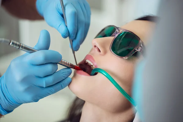 Healthy Smile. Beautiful Female Smile . Orthodontic Treatment. Dental care Concept. Dental inspection is being given to  Beautiful Woman surrounded by dentist and his assistant