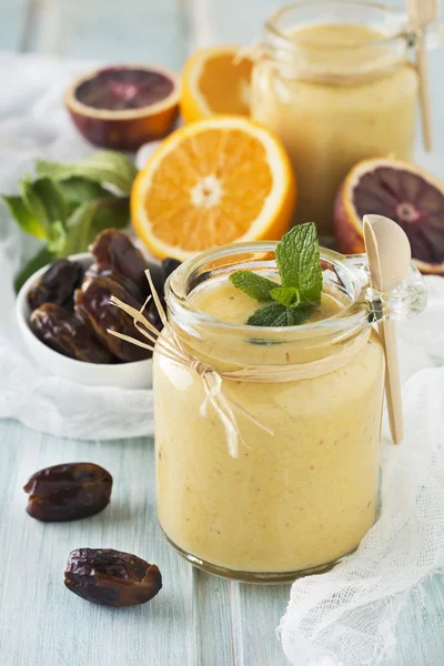 Healthy and fresh orange and date fruit smoothie on blue wooden table. Selective focus.