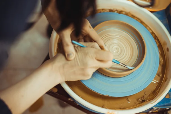 Man paints a clay plate
