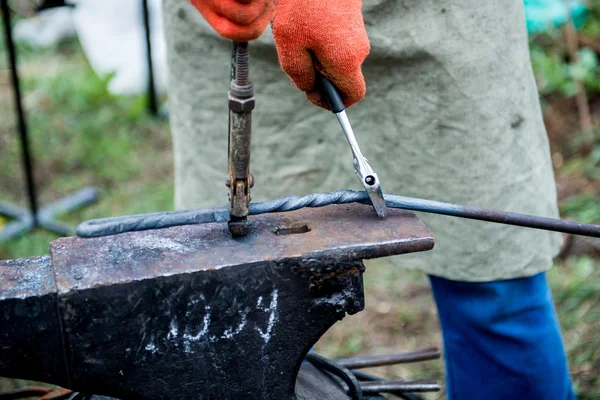 Blacksmith works on an anvil.