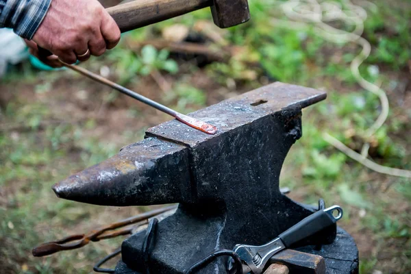 Blacksmith works on an anvil.