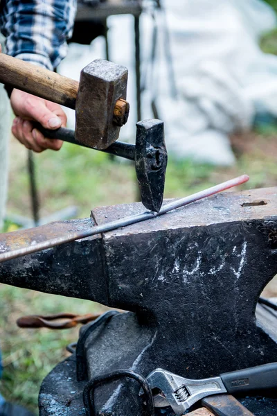 Blacksmith works on an anvil.