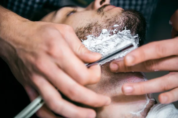 The barber cuts the beard man.