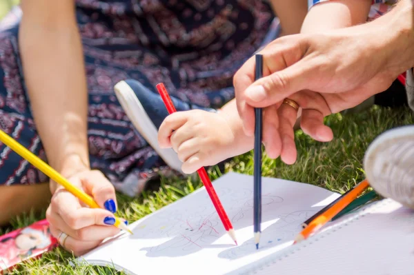 Dad, mom and toddler draws pencils.