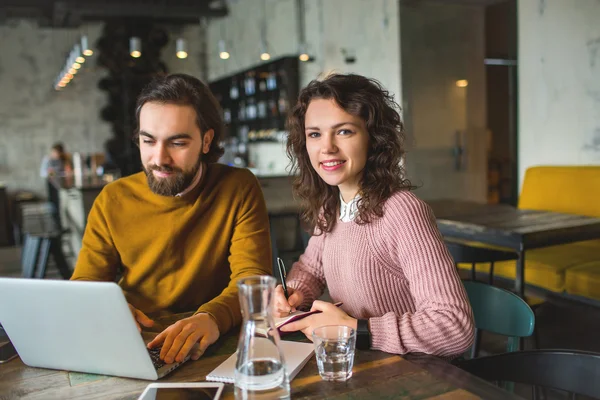 Young hipster male and female working laptop together in cafe