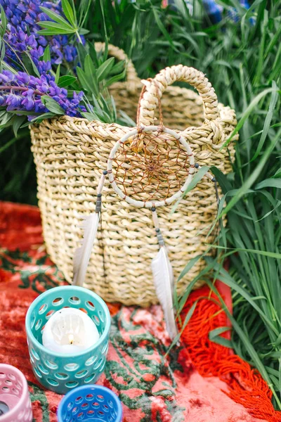 Basket with flowers and dream catcher on red blanket