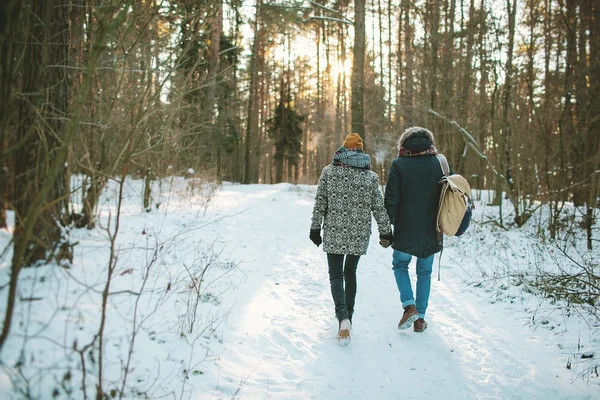 Young hipster couple having a walk in winter forest