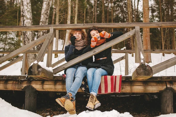 Couple playing harmonica together in winter park sitting on floo