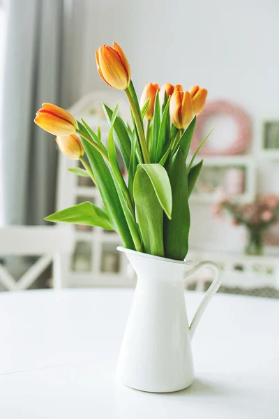 Beautiful orange flowers in vase on rustic kitchen table