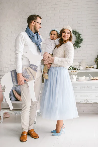 Happy young family smiling and hugging in bright loft studio