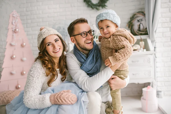 Happy young family smiling and hugging in bright loft studio