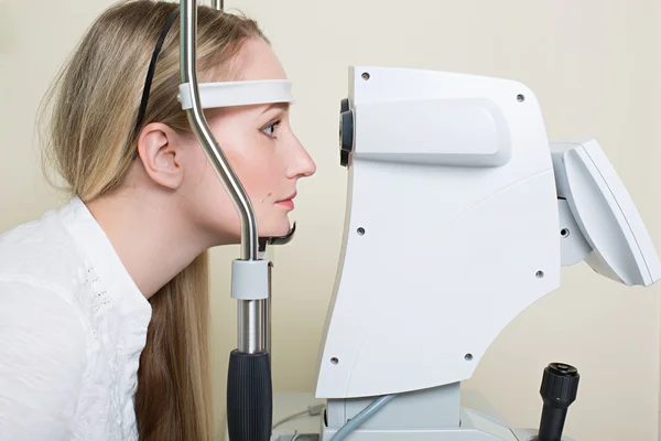 Young woman having her eyes examined by an eye handsome elderly doctor