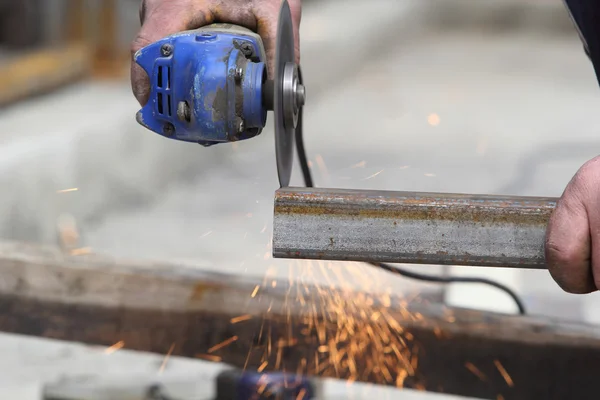 Worker cutting metal with many sharp sparks