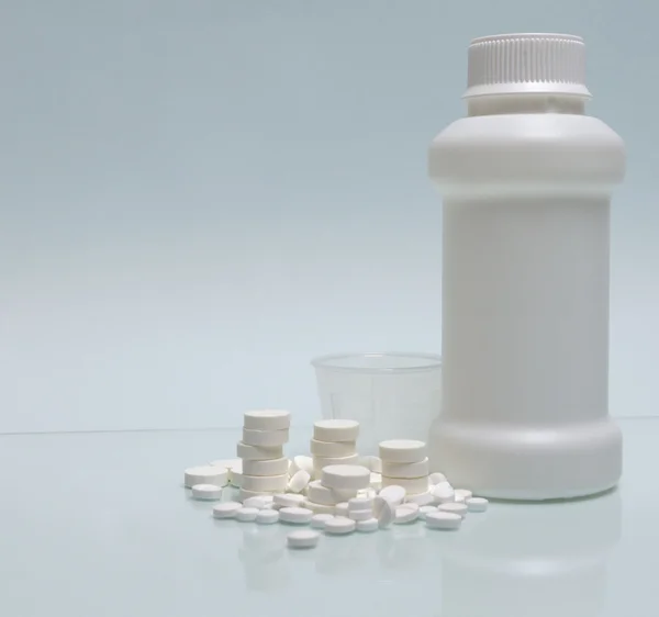 White tablets, white container for mixture and measuring cup