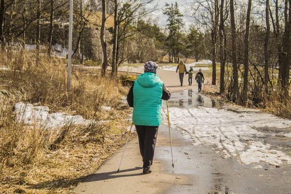 Old woman with hiking stick in spring nature outdoors.