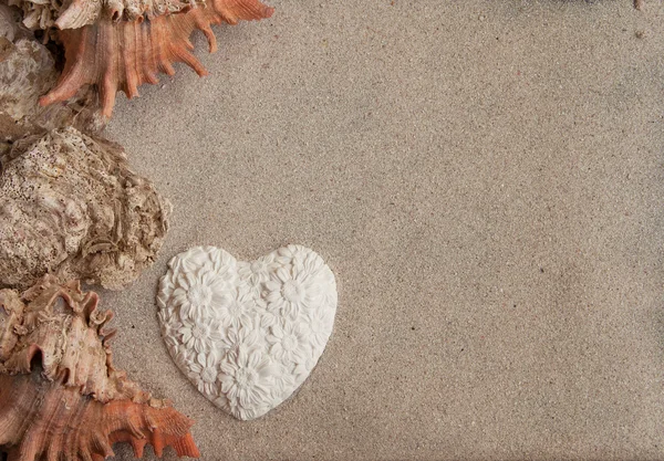 Seashells heart and sand background horizontal