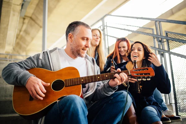 Happy group of friends enjoying  playing guitar and singing toge