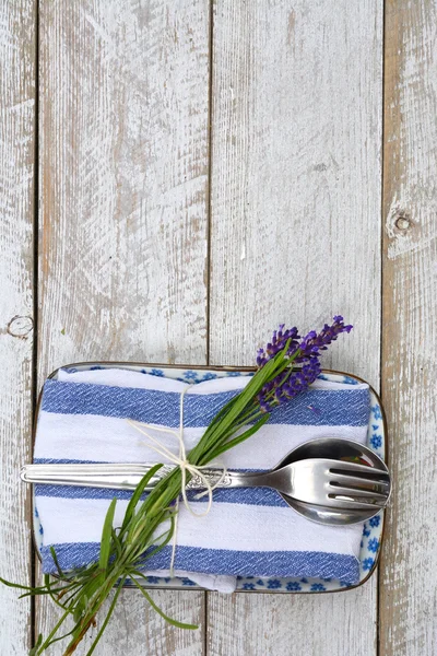 Silver cutlery and a blue white napkin kitchen towel with lavender decoration and empty copy space in rustic vintage country style