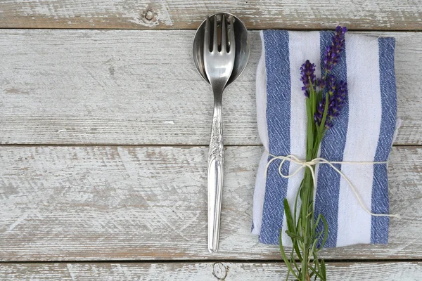 Silver cutlery and a blue white napkin kitchen towel with lavender decoration and empty copy space in rustic vintage country style