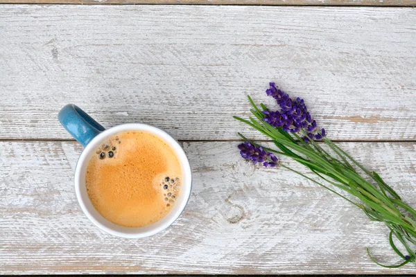 Blue coffee cup on a old white wooden shelves background with lavender flowers and kitchen towel and empty copy space.