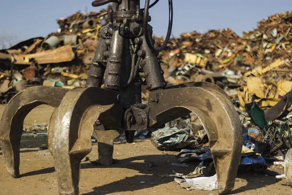 Cactus grab bucket on junkyard with blurred pile background.