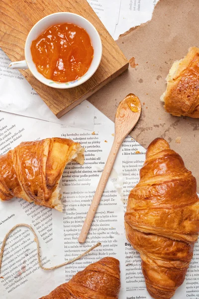 Croissant on a background of the newspapers with jam
