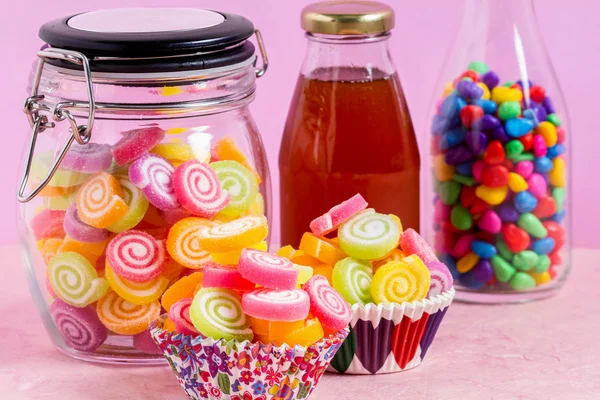 Candy with honey in jar on table on pink background