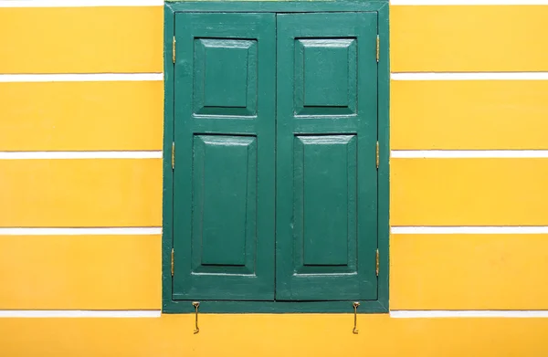 Window green pastel frame on  old yellow building stucco wall, b