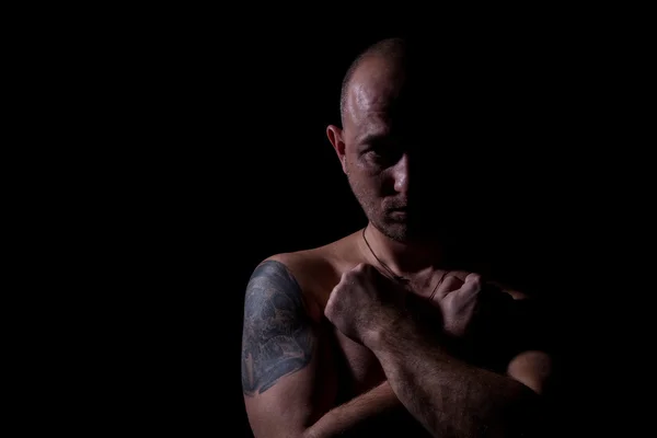 Silhouette of serious man with crossed hands and tattoo