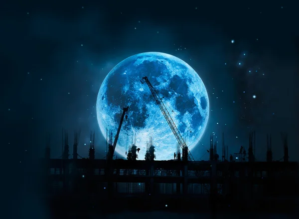 Construction site with cranes and workers in full blue moon at night