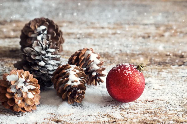 Red christmas ornament pine cones with snow on wooden