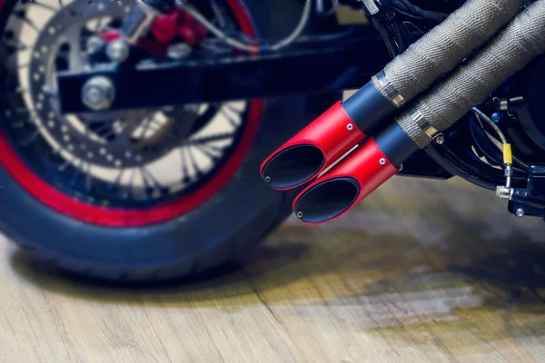Red motorcycle exhaust pipe, modern style exhaust on wooden background