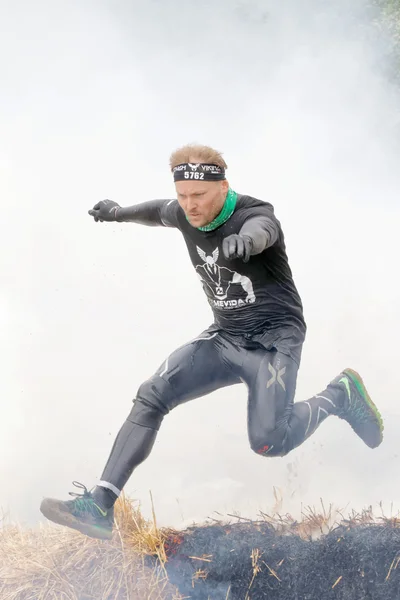 Man in black clothes jumping over fire and smoke