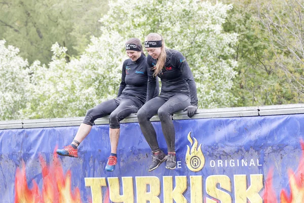 Smiling women mount a wall obstacle