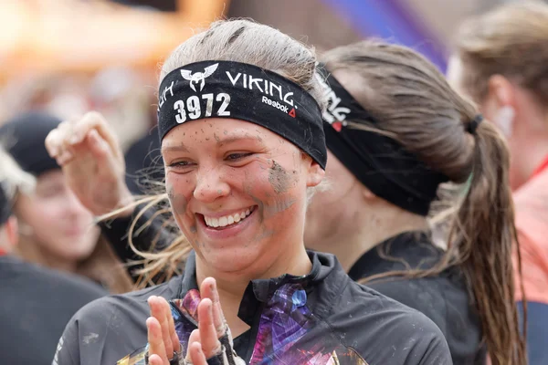 Smiling happy woman awith mud in her face after finishing a race