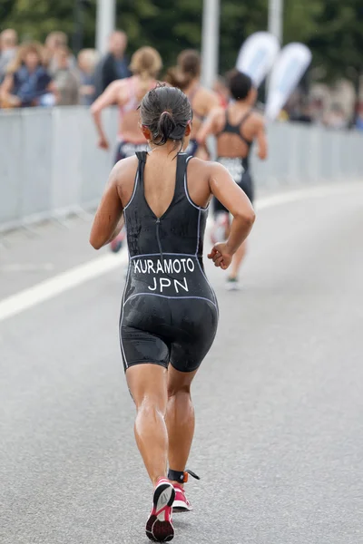 Rear view of triathlete Aoi Kuramoto running in the rain