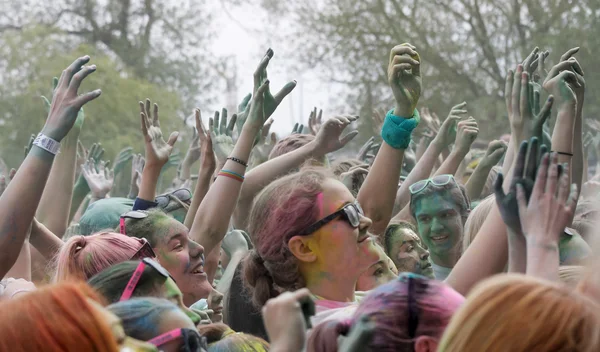 Happy audience with arms in the air and color powder in the air