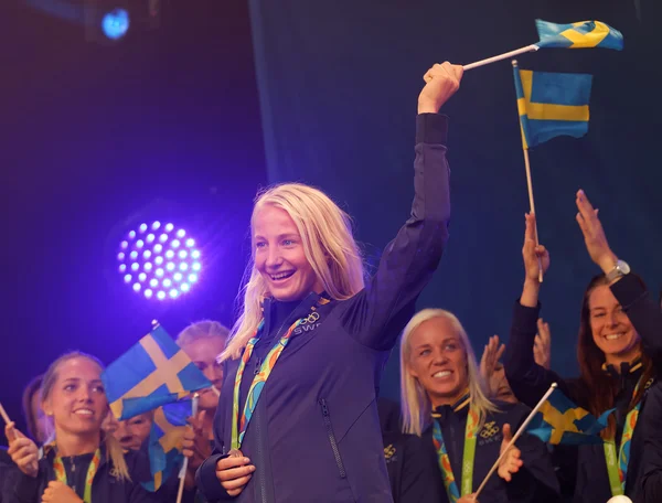 Happy swedish female wrestler Sofia Mattson waiving a flag