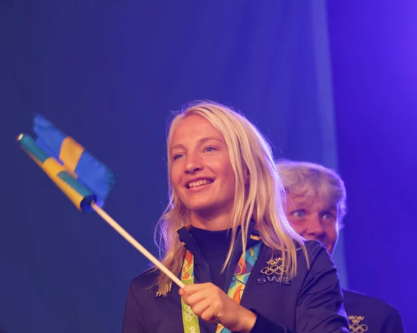 Happy swedish female wrestler Sofia Mattson waiving a flag